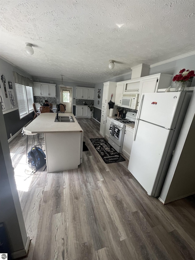 kitchen featuring dark hardwood / wood-style flooring, white appliances, a kitchen island with sink, sink, and white cabinets