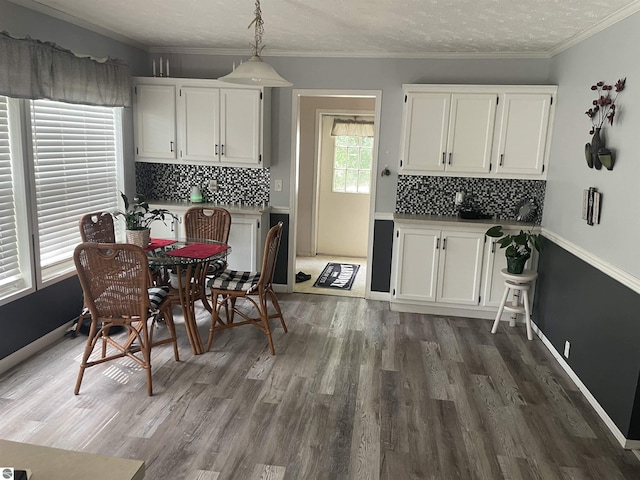 dining space with a textured ceiling, crown molding, and dark hardwood / wood-style floors