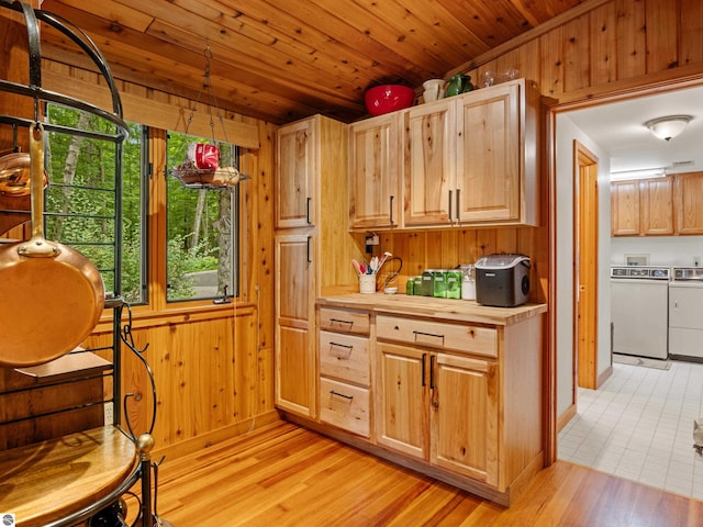 kitchen featuring light brown cabinetry, washer and clothes dryer, light hardwood / wood-style flooring, wooden ceiling, and wood walls