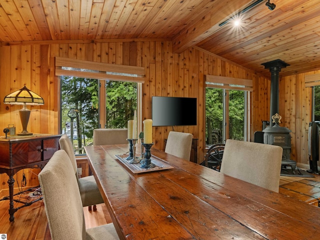 dining room with a wood stove, wooden ceiling, lofted ceiling with beams, and light hardwood / wood-style floors