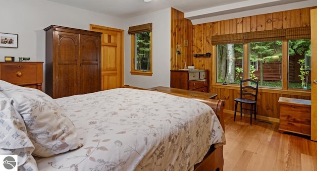 bedroom featuring wood walls and light hardwood / wood-style flooring