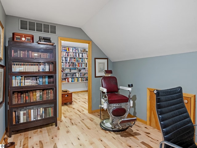 sitting room with built in shelves, light hardwood / wood-style floors, and vaulted ceiling