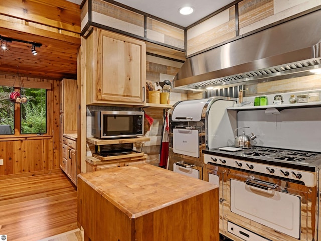 kitchen featuring butcher block counters, range hood, wooden walls, a kitchen island, and light wood-type flooring