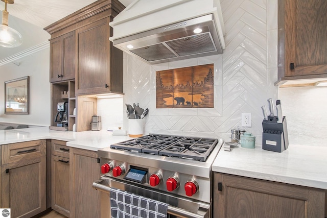 kitchen with high end range, decorative light fixtures, tasteful backsplash, ornamental molding, and custom range hood