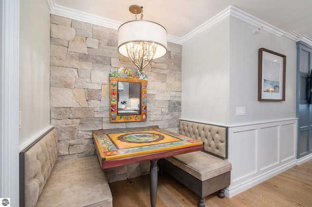 dining space with breakfast area, light hardwood / wood-style flooring, ornamental molding, and an inviting chandelier