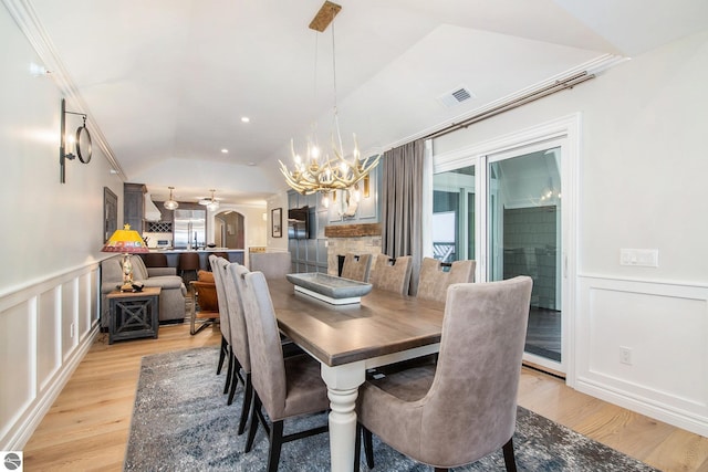 dining area featuring lofted ceiling, light wood-type flooring, plenty of natural light, and ceiling fan with notable chandelier