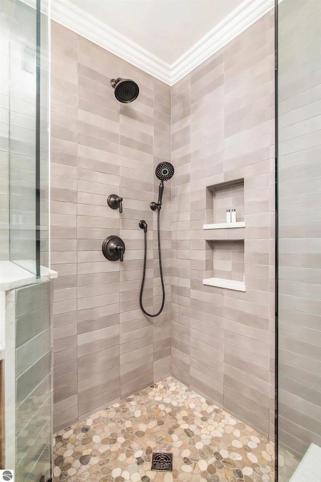 bathroom with tiled shower and crown molding