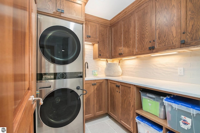 laundry room featuring cabinets, stacked washer / dryer, light tile patterned floors, and sink