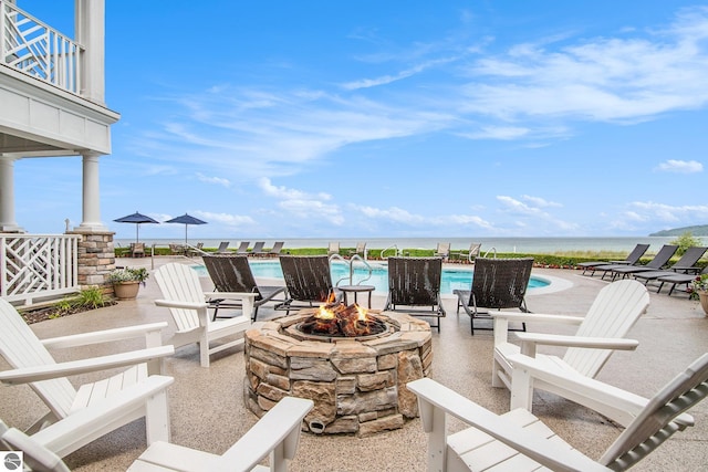 view of patio / terrace with a water view, a community pool, a balcony, and a fire pit