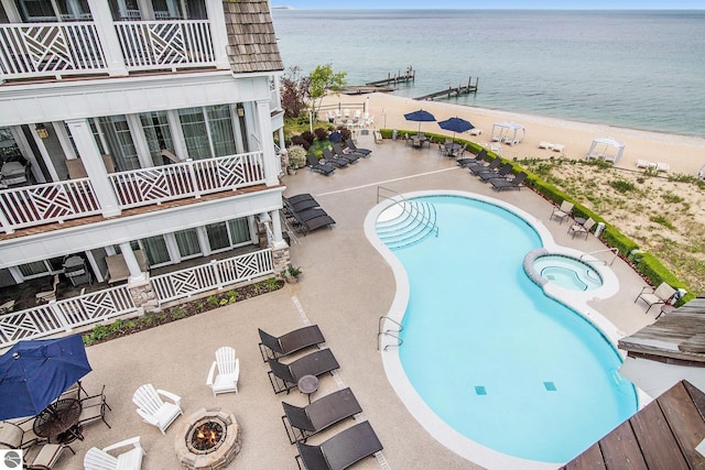 view of pool with a beach view, a water view, and a patio