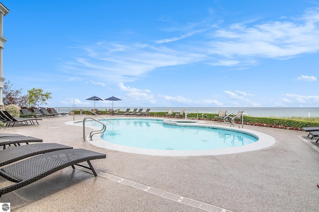 view of pool featuring a water view, a patio, and an in ground hot tub