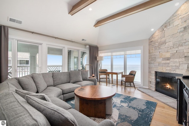 living room featuring light wood-type flooring, lofted ceiling with beams, a water view, and a fireplace