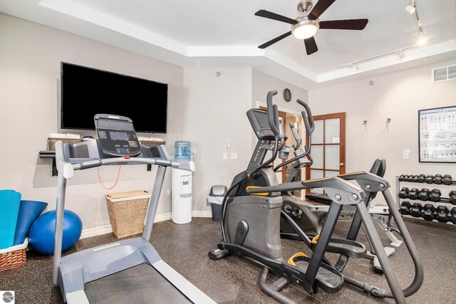 workout area with ceiling fan, a raised ceiling, and track lighting