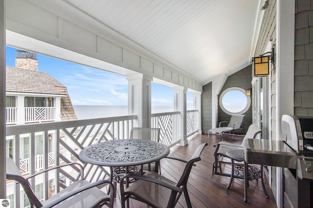 sunroom featuring lofted ceiling and a water view