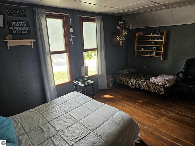 bedroom with multiple windows, wood walls, and dark hardwood / wood-style flooring