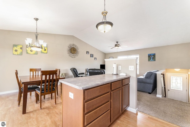 kitchen featuring ceiling fan with notable chandelier, decorative light fixtures, lofted ceiling, kitchen peninsula, and light hardwood / wood-style flooring