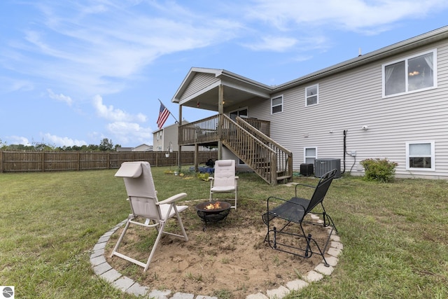 back of house featuring central AC, a wooden deck, a lawn, and an outdoor fire pit