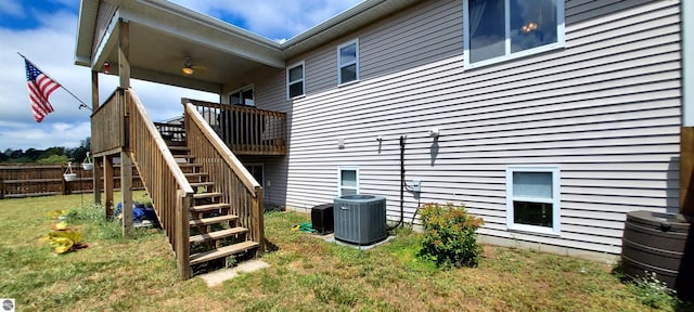 view of side of property featuring a yard, central AC unit, and a deck