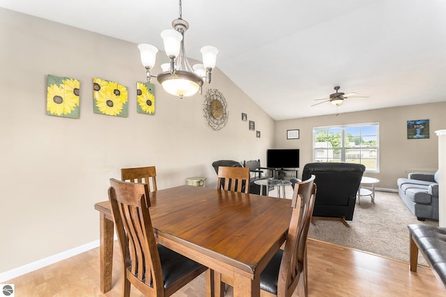 dining area with ceiling fan with notable chandelier, vaulted ceiling, and light hardwood / wood-style floors