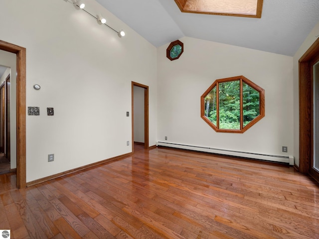 unfurnished room with vaulted ceiling with skylight, light wood-type flooring, and a baseboard heating unit