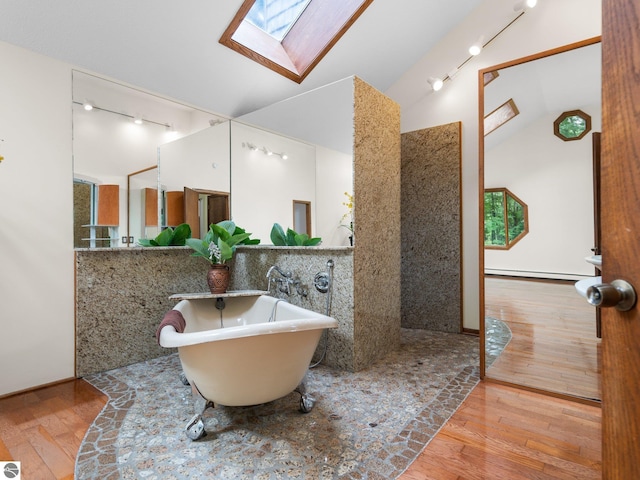 bathroom featuring sink, a baseboard heating unit, a tub to relax in, vaulted ceiling with skylight, and hardwood / wood-style flooring