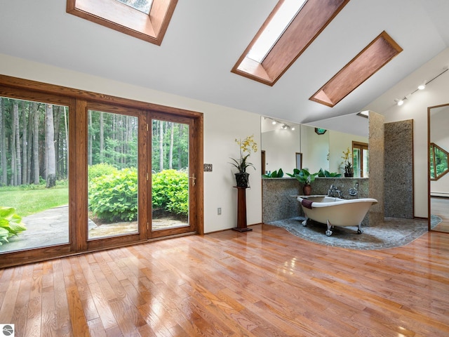 interior space with lofted ceiling with skylight, light hardwood / wood-style flooring, and a baseboard radiator