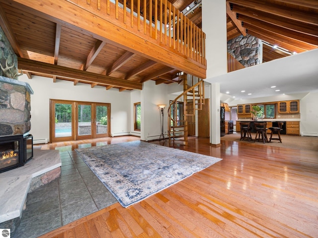 living room with high vaulted ceiling, a stone fireplace, hardwood / wood-style flooring, beamed ceiling, and wood ceiling