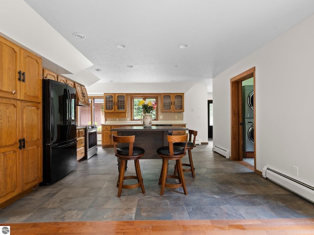 kitchen with black refrigerator, a kitchen bar, a baseboard heating unit, electric range, and a kitchen island