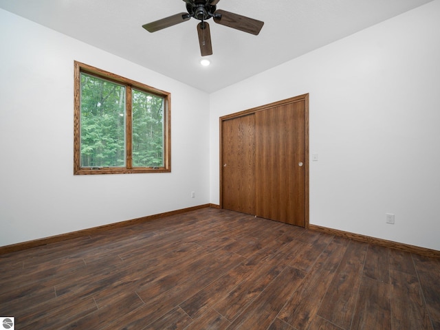 unfurnished bedroom featuring ceiling fan, dark hardwood / wood-style floors, and a closet