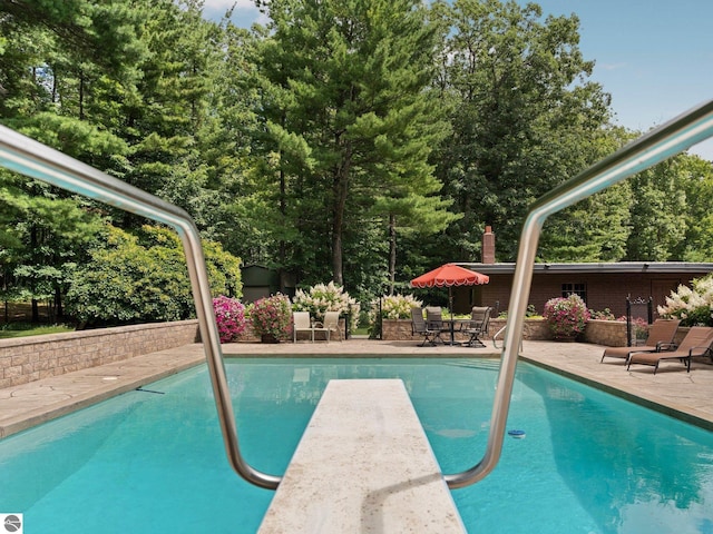 view of swimming pool with a diving board and a patio area