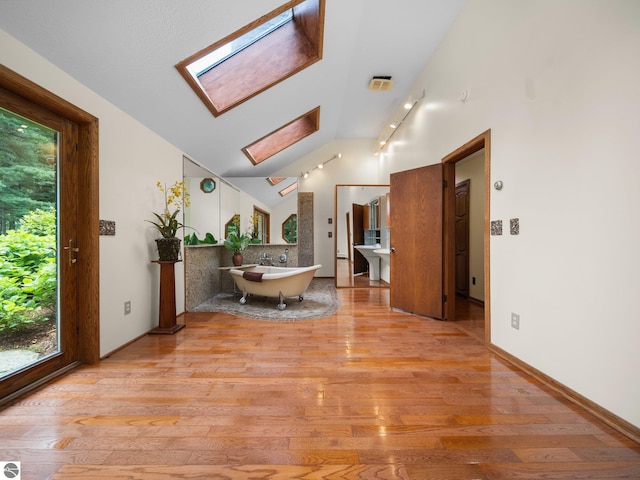 interior space with light hardwood / wood-style floors and lofted ceiling with skylight