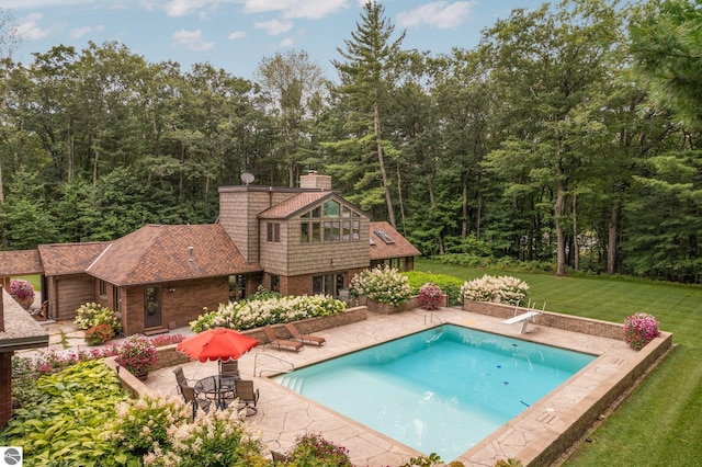 view of swimming pool featuring a yard, a patio, and a diving board