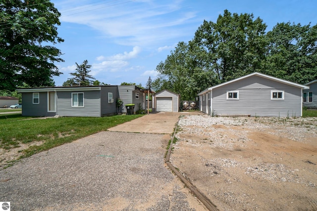 exterior space with a garage, a front lawn, and an outbuilding