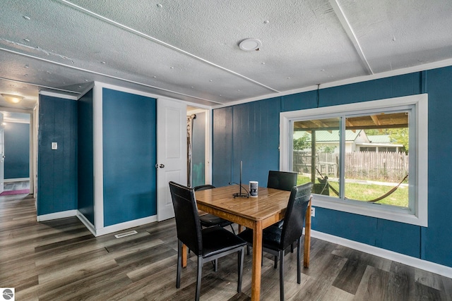 dining area with a textured ceiling and dark wood-type flooring