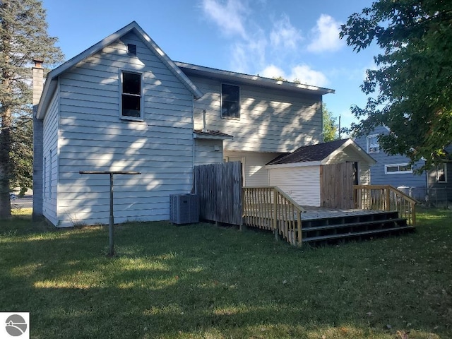 rear view of property featuring a wooden deck, a lawn, and central AC