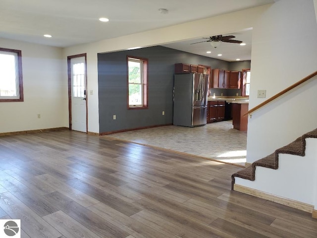 unfurnished living room featuring light wood-type flooring, a healthy amount of sunlight, and ceiling fan