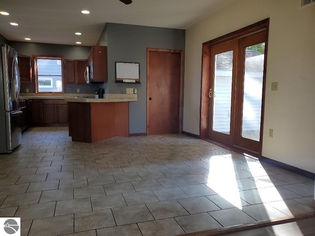 kitchen featuring kitchen peninsula, ceiling fan, stainless steel refrigerator, and light tile patterned floors