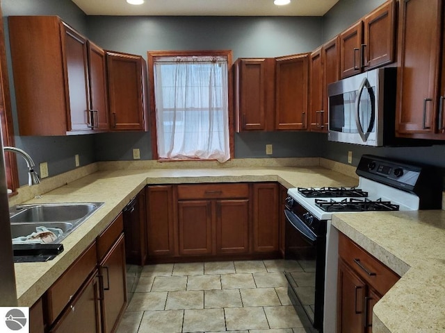 kitchen with white gas range oven, black dishwasher, sink, and light tile patterned floors