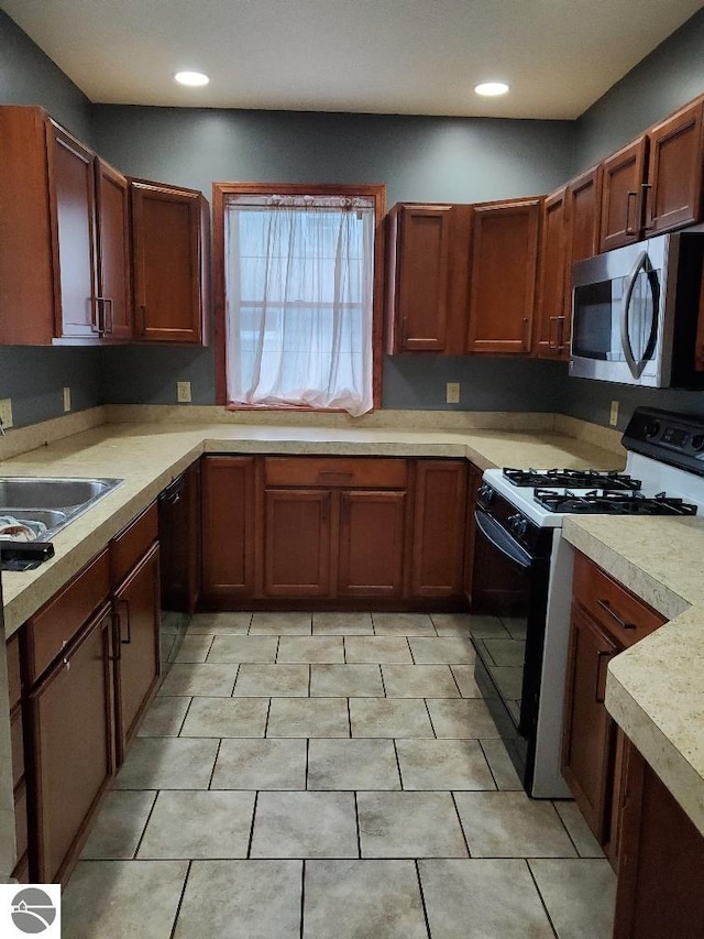 kitchen featuring black dishwasher, sink, light tile patterned floors, and white range with gas cooktop