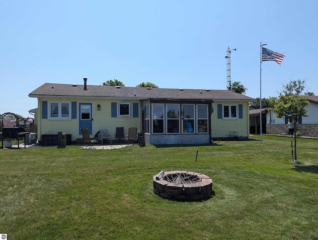 rear view of property with a yard and a fire pit