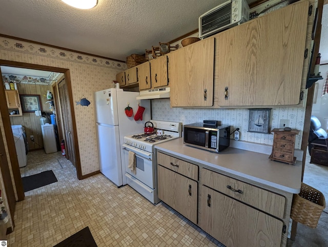 kitchen featuring washer / dryer, a textured ceiling, white appliances, and light tile patterned floors