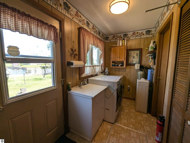 laundry area with wood walls, cabinets, light tile patterned floors, and plenty of natural light