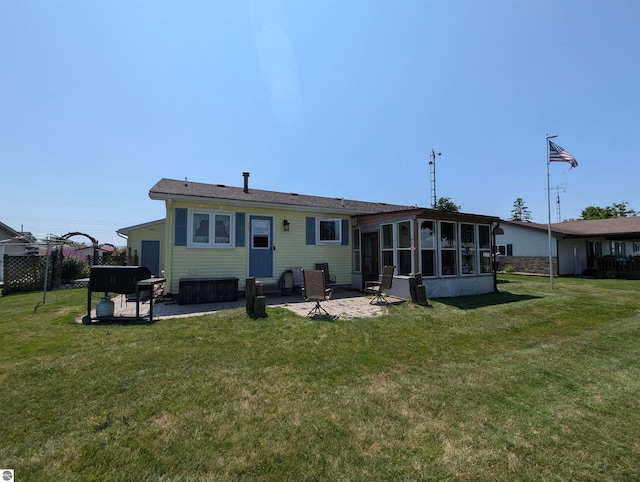 rear view of property featuring a sunroom, a patio, and a lawn