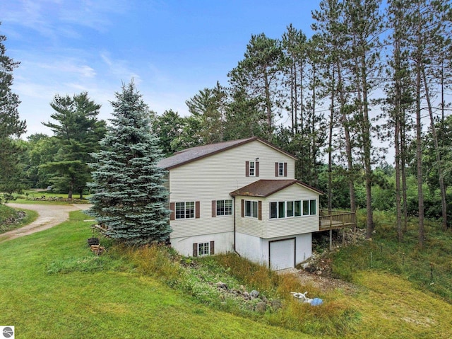 view of side of home featuring a garage, a deck, and a yard