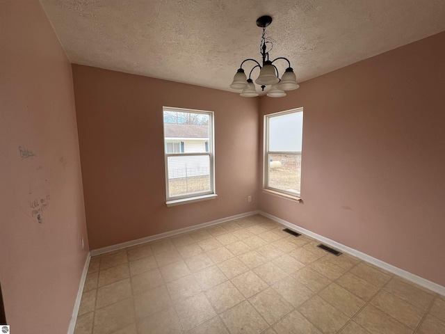 spare room with a notable chandelier and a textured ceiling