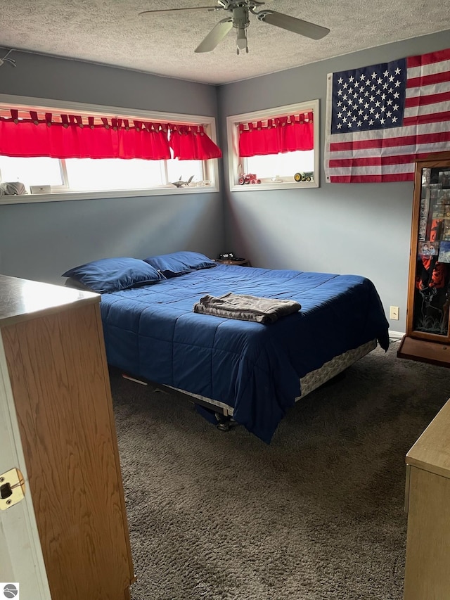 bedroom with a textured ceiling, dark colored carpet, and ceiling fan