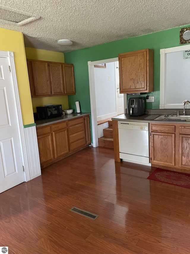 kitchen with sink, dark hardwood / wood-style flooring, dishwasher, and a textured ceiling