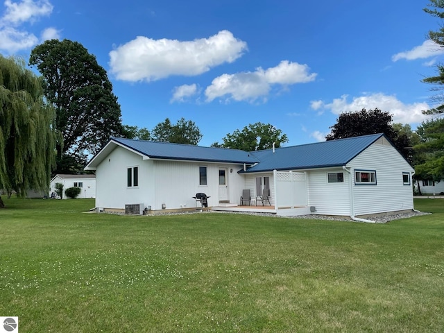 rear view of house featuring central AC unit, a yard, and a patio area