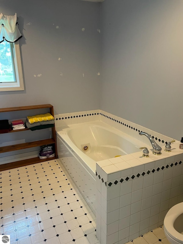 bathroom with tile patterned flooring, toilet, and a relaxing tiled tub