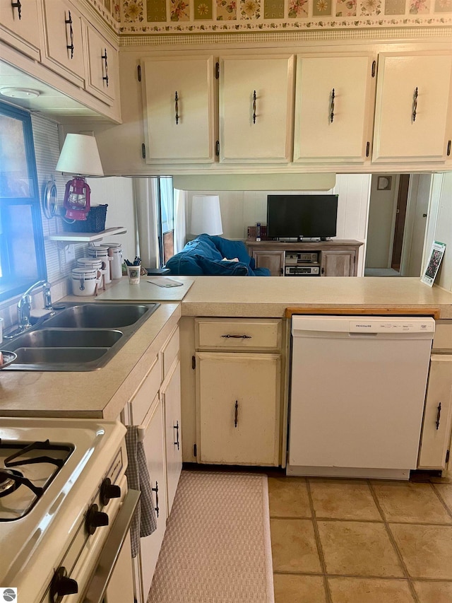 kitchen featuring stove, white cabinets, sink, light tile patterned floors, and dishwasher